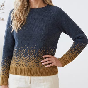 May include: A long-sleeve knit sweater featuring a crew neckline and a ribbed hem and cuffs. The garment transitions from a solid dark blue upper section to a mustard yellow lower section, decorated with a repeating abstract pattern in both colors.