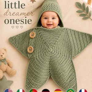 Può includere: Una tutina all'uncinetto a forma di stella color verde salvia con cappuccio e due grandi bottoni in legno sul lato. Il testo 'little dreamer onesie' è stampato in lettere verde scuro sopra l'indumento, accompagnato da una piccola stella e tre cuori.