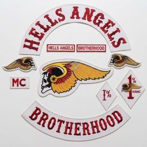 May include: A collection of embroidered patches featuring a large white arched patch with red text reading HELLS ANGELS, a matching BROTHERHOOD arch, a central winged skull emblem, two smaller winged skull patches, and two diamond-shaped 1% patches.