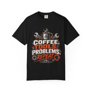 Könnte beinhalten: Ein schwarzes Kurzarm-T-Shirt mit einem Grafikdruck, der eine Kaffeetasse, Schraubenschlüssel und Zahnräder zeigt. Der Text lautet COFFEE. TOOLS. PROBLEMS. REPEAT. zusammen mit dem Markennamen AFTER SHIFT CO. unten in einer abgenutzten Schrift.