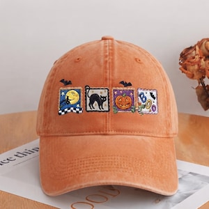 May include: An orange baseball cap featuring four embroidered square patches. The patches depict a witch on a broomstick against a full moon, a black cat, a jack-o'-lantern, and the word BOO in blue and orange letters with small bats.