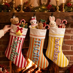 Puede incluir: Tres calcetines de Navidad colgados en fila. El primero es de rayas rojas y blancas con el nombre Sophia en verde. El segundo es de rayas verdes y naranjas con el nombre Mom en azul. El tercero es de rayas amarillas y blancas con el nombre Winter en morado.