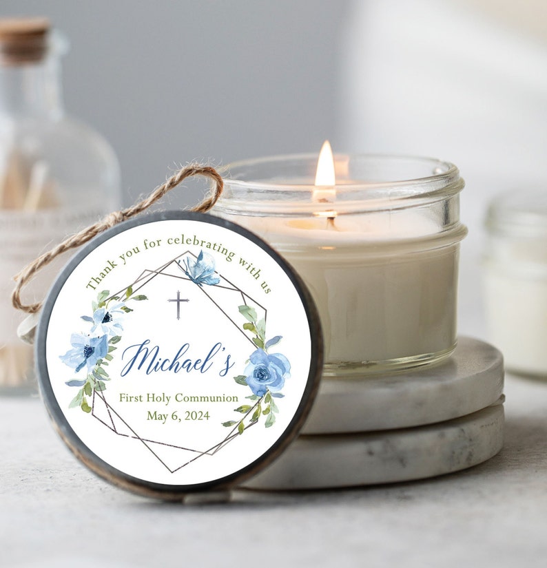 Lit soy candle favor in 4oz mason jar with pewter-color lid and jute tie, custom label has a eucalyptus wreath design in white, silver, blue and green, It reads, Thank you for celebrating with us, and can be personalized with a name, event and date