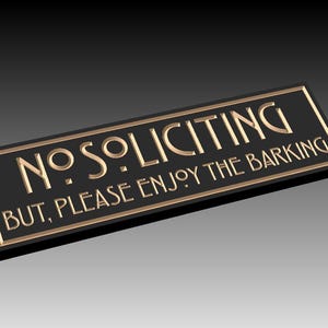 Könnte beinhalten: Ein rechteckiges, schwarzes Schild mit goldfarbenen Buchstaben. Der Text lautet „NO SOLICITING BUT, PLEASE ENJOY THE BARKING“. Das Schild hat einen goldenen Rahmen und besteht wahrscheinlich aus Metall oder einem ähnlichen Material.
