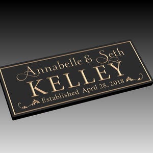 Puede incluir: Placa rectangular negra con letras doradas. La placa dice "Annabelle & Seth Kelley" encima de "KELLEY" y "Established April 28, 2018". Hay adornos decorativos en la placa.
