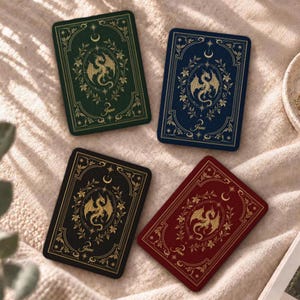 May include: Four rectangular cards in green, blue, black, and red, each featuring a gold-colored dragon illustration centered within an ornate floral frame. Above each dragon is a crescent moon and stars, with the name Jane printed at the bottom.