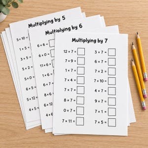 Könnte beinhalten: Ein Stapel weißer Mathe-Arbeitsblätter mit schwarzem Text, die Einmaleins-Tabellen für 5, 6 und 7 zeigen. Jedes Blatt enthält Gleichungen mit leeren Kästchen für Antworten. Drei gelbe Holzbleistifte mit Radiergummis liegen rechts daneben.