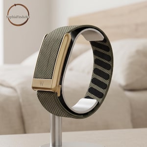 May include: A fitness tracker band featuring a textured olive green fabric strap and a metallic gold clasp with a W logo. The interior of the band is lined with black padding, and the device is mounted on a silver stand for display purposes.