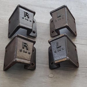 May include: Four dark brown metal corner brackets with an L-shaped design. Two brackets are marked with the letter R and the text C 14 R, while the other two are marked with the letter L and the text C 14 L. Each bracket features pre-drilled holes.