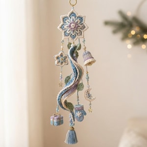 May include: A decorative hanging ornament featuring a large central crochet snowflake in shades of blue, white, and lavender. It includes dangling crochet charms shaped like a bell, a crescent moon, a mitten, and a gift box, accented with beads.