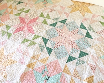 May include: A quilt with a patchwork design featuring a variety of floral patterns in shades of pink, green, and yellow. The quilt is quilted with a swirling pattern.