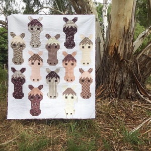 May include: A quilt with a white background and 13 horse-shaped patches in various shades of brown, pink, and white. The patches are arranged in a grid pattern.