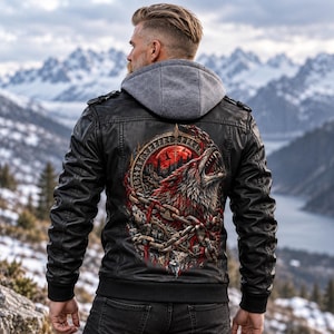 Peut inclure: Une veste noire avec une capuche grise présentant un motif dorsal détaillé représentant un loup hurlant entouré de chaînes et d'une bordure runique circulaire. La veste comprend des épaulettes, des manches longues et des poignets côtelés.