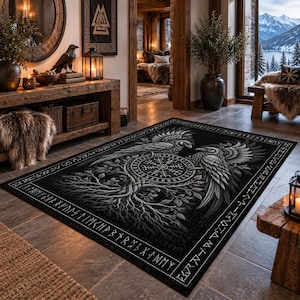 Può includere: Un tappeto rettangolare con un design in bianco e nero raffigurante due corvi l'uno di fronte all'altro, un simbolo centrale della bussola Vegvisir e un intricato motivo dell'albero della vita. Il bordo è decorato con caratteri runici.