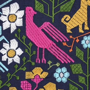 Pode incluir: Tecido bordado com um padr&atilde;o repetido de flores estilizadas, um p&aacute;ssaro rosa e um c&atilde;o amarelo sobre um fundo azul marinho. As flores incluem margaridas brancas, flores amarelas e rosas e flores azuis. Folhas e caules verdes completam o design.