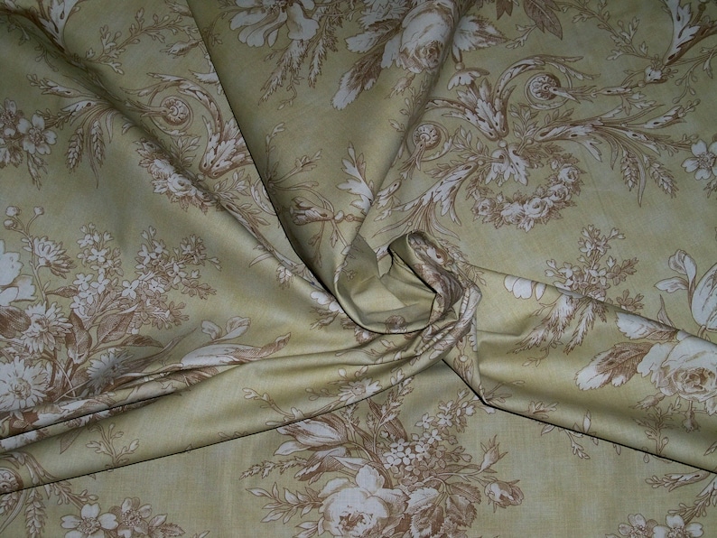 Puede incluir: Una tela beige con un patr&oacute;n floral marr&oacute;n. La tela est&aacute; doblada y drapeada, mostrando el patr&oacute;n en detalle.