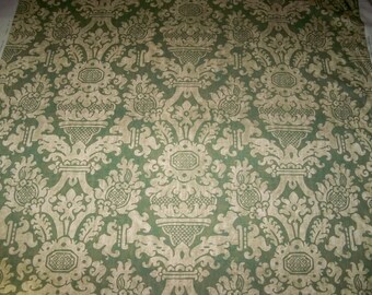 Può includere: Un tessuto verde con un motivo damascato beige. Il motivo presenta un disegno ripetitivo di fiori e foglie stilizzati.
