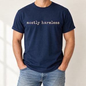 Peut inclure: Un t-shirt bleu marine à manches courtes avec le texte mostly harmless imprimé en couleur crème clair sur la poitrine. Le vêtement présente une encolure ronde classique et des manches courtes avec une finition ourlée simple sur les bords.