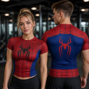 May include: Two short-sleeved athletic shirts featuring a red and blue colour scheme with a black spider web pattern. The front of the left shirt displays a black spider emblem, while the back of the right shirt features a large red spider logo.