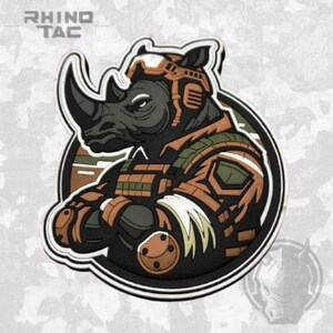 Peut inclure: Un écusson circulaire représentant un rhinocéros stylisé portant un équipement tactique, incluant un casque et un gilet dans des tons marron, vert olive et noir. Le texte RHINO TAC est imprimé dans le coin supérieur gauche du motif.