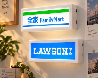 Könnte beinhalten: Zwei rechteckige LED-Leuchtkästen mit weißem Rahmen, die an einer Wand montiert sind. Der obere Leuchtkasten zeigt das FamilyMart-Logo mit grünen und blauen Streifen. Der untere Leuchtkasten zeigt das blau-weiße Lawson-Logo mit englischem und chinesischem Text.