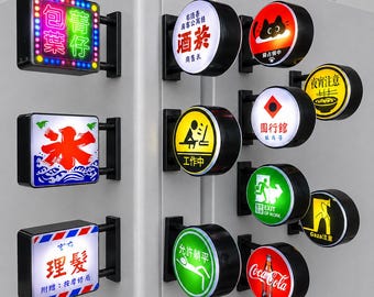 Könnte beinhalten: Eine Sammlung von wandmontierten, beleuchteten Schildern in verschiedenen quadratischen und runden Ausführungen. Die Schilder zeigen diverse Grafiken, darunter Texte auf Chinesisch, Englisch und Japanisch sowie Symbole wie eine Katze und eine Flasche.