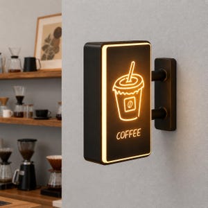 Puede incluir: Un letrero rectangular negro montado en la pared que presenta un contorno naranja brillante estilo neón de una taza de café con pajita y la palabra COFFEE impresa en naranja debajo del gráfico. El letrero tiene un borde iluminado y soporte.