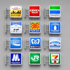 Puede incluir: Una colección de doce letreros luminosos cuadrados montados en la pared con varios logotipos de marcas japonesas, incluidos Asahi, Yakult, FamilyMart, Meiji, Matsumoto Kiyoshi, Lawson, Pocari Sweat, Tokyo Metro, Osaka Metro, JR East y 7-Eleven.