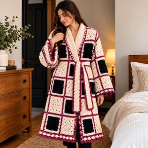 May include: A long-sleeved crochet cardigan featuring a grid pattern of alternating cream and black square motifs. The garment is edged with a deep burgundy border and includes a matching tie belt at the waist, creating a structured silhouette.