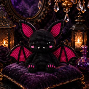 May include: A crocheted bat plush toy featuring a black body with vibrant pink inner ears and wing membranes. The bat has large black safety eyes, two small white fangs, and pink stitched cheeks, with pink accents on its feet and wing tips.