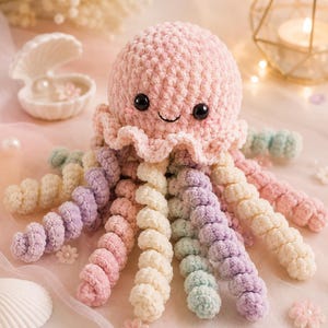 May include: A crocheted jellyfish plush toy with a soft, light pink rounded head, black plastic eyes, and a small embroidered smile. The jellyfish features multiple long, spiraling tentacles in alternating pastel shades of cream, lavender, mint green, and pink.
