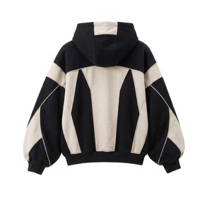 The back view of an oversized, heavyweight colorblock hoodie in black and off-white/beige, styled with retro Y2K streetwear details against a plain white background.
