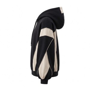 A side profile view showing the opposite side of the black and off-white/beige colorblock streetwear hoodie, isolated on a plain white background.