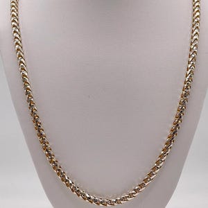 May include: A two-tone franco chain necklace featuring alternating links of polished yellow gold and silver-toned metal. The chain has a rounded, woven square-link design that creates a continuous, textured appearance throughout the entire length.