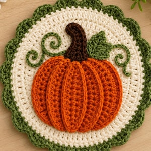 May include: A round crochet coaster featuring a cream-colored center with a scalloped dark green border. In the middle, an orange pumpkin with a dark brown stem and a green leaf is stitched, accented by two dark green curly vine tendrils.