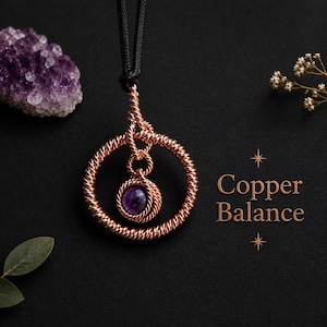 May include: A pendant featuring a circular copper wire frame with a twisted texture, suspending a smaller matching wire-wrapped circle containing a round purple amethyst gemstone. The piece hangs from a black cord and includes the text Copper Balance.