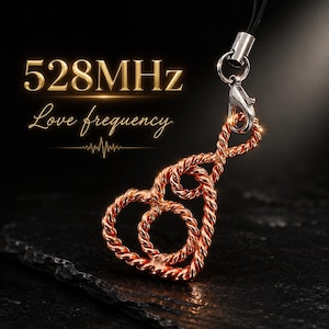 May include: A copper-colored metal charm shaped like an infinity symbol intertwined with a heart. The charm hangs from a silver-toned lobster clasp and a black cord. Text on the image reads 528MHz Love frequency with a small heartbeat line.