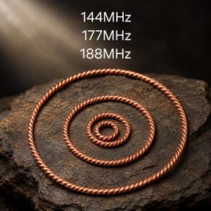 May include: Three concentric copper rings with a twisted, rope-like texture. The text 144MHz, 177MHz, and 188MHz is displayed above the rings. The metallic copper material has a warm, reddish-brown tone and a polished finish.