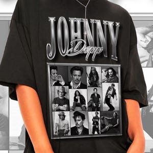 Könnte beinhalten: Ein schwarzes kurzärmeliges T-Shirt mit einem großen Grafikdruck von Johnny Depp. Das Design enthält den Text "JOHNNY Depp" in einer metallischen Schrift über einer Collage aus zwölf Schwarz-Weiß-Fotos, die verschiedene Filmrollen zeigen.