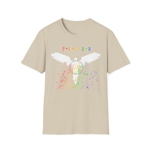 Könnte beinhalten: Ein beiges Kurzarm-T-Shirt mit dem Text PAGAN in Regenbogenfarben über einer weißen Silhouette einer geflügelten Figur. Die Figur ist von einem kreisförmigen Blumenkranz und einem lebendigen Regenbogen-Farbspritzereffekt an der Basis umgeben.