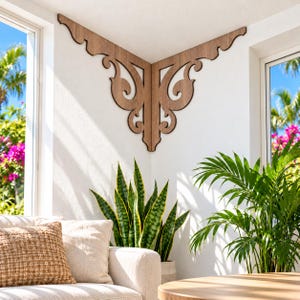 Pode incluir: Um suporte de canto de madeira castanha com um design decorativo de volutas e recortes. O suporte está montado rente à parede branca no canto superior onde duas paredes se encontram, estendendo-se ao longo do teto em ambos os lados.
