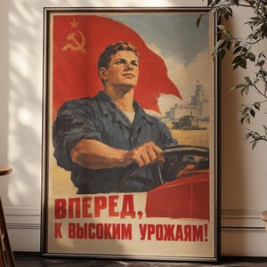 May include: A framed vintage-style propaganda poster featuring a man driving a tractor in a field. A large red flag with a yellow hammer and sickle is in the background. The text reads: ВПЕРЕД, К ВЫСОКИМ УРОЖАЯМ! The poster has a beige background.