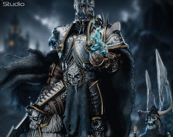 Op de afbeelding: Een gedetailleerd verzamelbeeldje van een krijger in versierd zilveren en gouden harnas met schedelmotieven, een kroon met stekels en een donkere, gerafelde cape. Het figuur houdt een gloeiend blauw energie-effect vast naast een skeletfiguur.