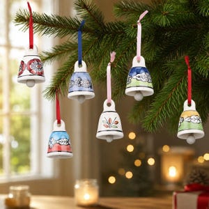May include: Six ceramic bell ornaments hanging from evergreen branches. Each bell features a unique hand-painted design with floral or leaf motifs in colours including red, blue, green, yellow, and white, suspended by matching satin ribbons.