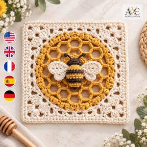 May include: A square crochet piece featuring a central honeycomb pattern in mustard yellow yarn, with a three-dimensional stuffed bee in black and yellow stripes attached to the center. The border is worked in cream yarn with a decorative shell stitch.
