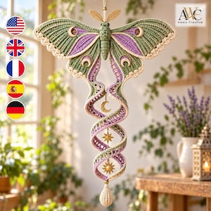 May include: A crocheted moth wall hanging featuring sage green and lavender wings with cream-coloured scalloped edges. A long, spiralling tail extends downwards, decorated with gold-toned metal charms including a crescent moon, a star, and a sun.