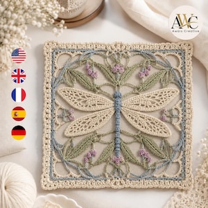 May include: A square crochet doily featuring a central dragonfly motif in light blue, surrounded by intricate green leaves and small purple floral accents. The piece is framed by a cream-colored lacy border on a neutral fabric background.