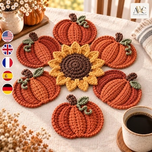 Pode incluir: Um conjunto de seis bases para copos em croché com cinco abóboras cor de laranja com caules castanhos e gavinhas verdes, e um girassol amarelo central com centro castanho, dispostos num padrão circular sobre uma superfície de tecido texturado.