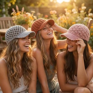 Pu&ograve; includere: Tre cappellini da baseball all'uncinetto in grigio chiaro, arancione ruggine e rosa polvere. Il cappellino grigio presenta un punto a rete aperto, quello color ruggine ha una trama a coste e quello rosa mostra un delicato motivo a conchiglia.