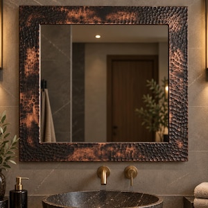Peut inclure: Un miroir mural carré doté d'un large cadre en métal martelé avec une finition en cuivre sombre et vieilli. La surface du cadre présente un motif texturé et alvéolé avec des tons alternés de brun foncé et de cuivre brillant sur tout le bord.